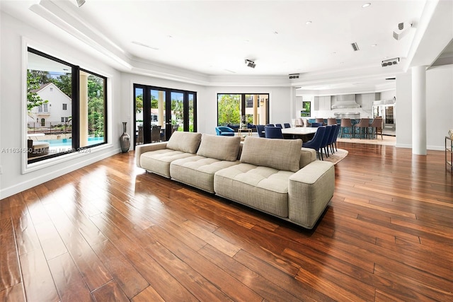 living area with hardwood / wood-style floors, visible vents, and baseboards