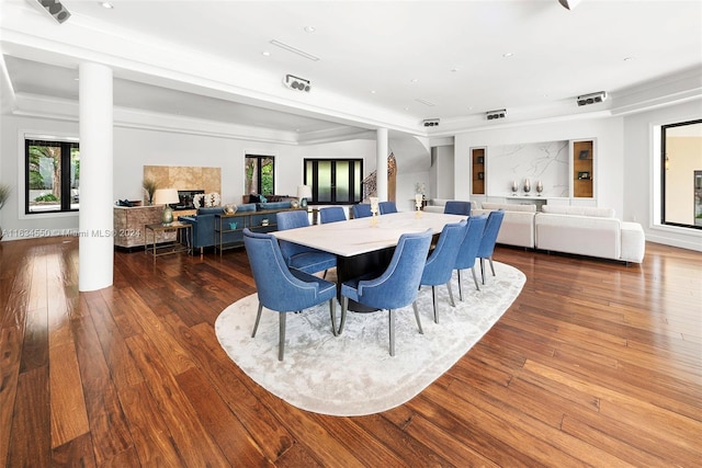 dining area featuring ornate columns, a raised ceiling, recessed lighting, and wood-type flooring