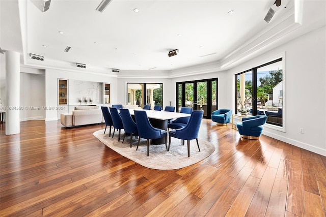 dining space with visible vents, a raised ceiling, baseboards, light wood finished floors, and french doors