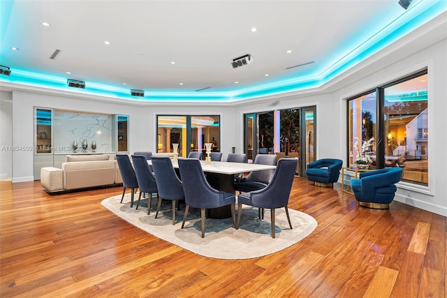 dining area with a tray ceiling and light wood-type flooring