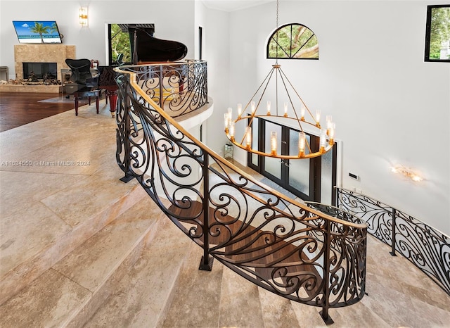 stairs featuring a wealth of natural light, stone finish flooring, ornamental molding, and an inviting chandelier