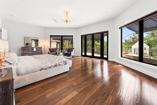 bedroom featuring access to outside, dark wood-type flooring, french doors, and a notable chandelier