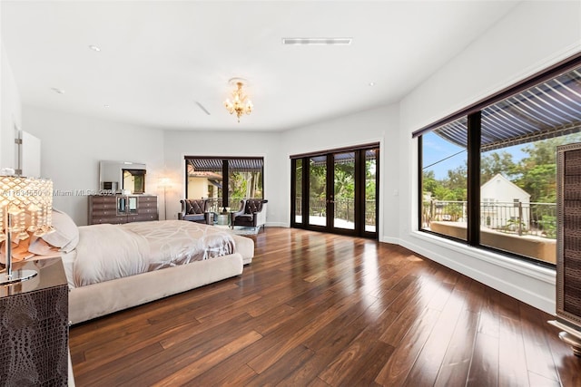 bedroom with a chandelier, multiple windows, dark hardwood / wood-style floors, and french doors