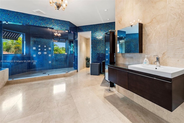 bathroom with tile walls, a chandelier, a shower with shower door, and vanity