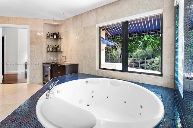 bathroom with tile walls, beverage cooler, a relaxing tiled tub, and sink