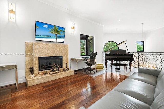 living room with wood-type flooring, crown molding, a premium fireplace, and baseboards