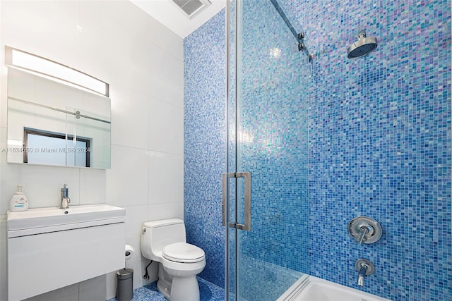 bathroom with vanity, tile walls, a shower with shower door, and toilet