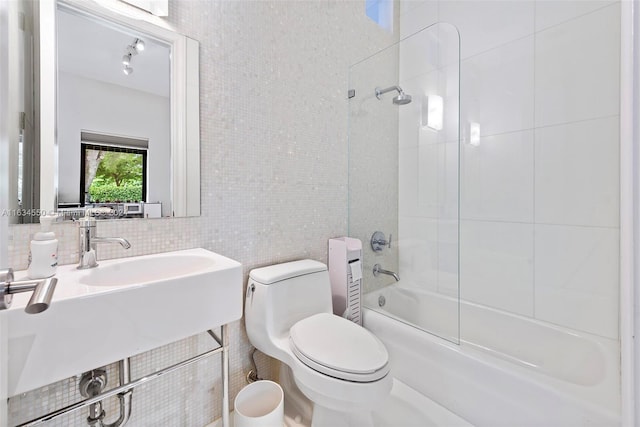 bathroom featuring tile walls, tasteful backsplash, tiled shower / bath, and toilet