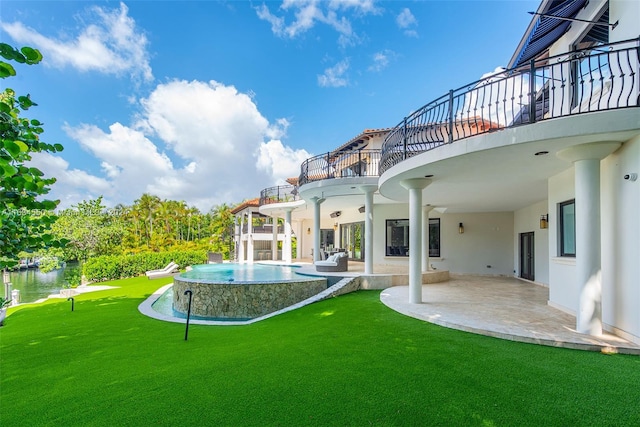 rear view of house featuring a balcony, a patio, a water view, and a yard