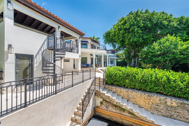 exterior space featuring stucco siding, stairway, and a tile roof