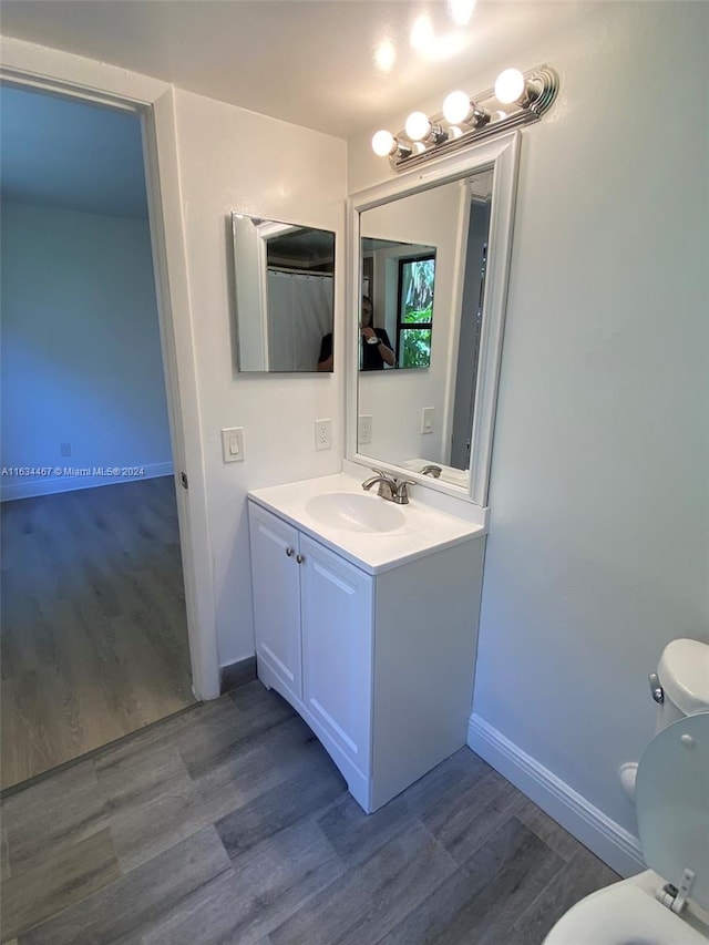 bathroom with vanity, toilet, and wood-type flooring