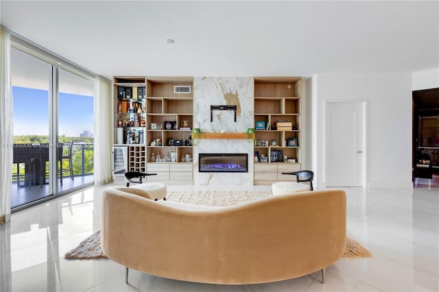 living room with a high end fireplace, expansive windows, wine cooler, built in shelves, and light tile patterned flooring