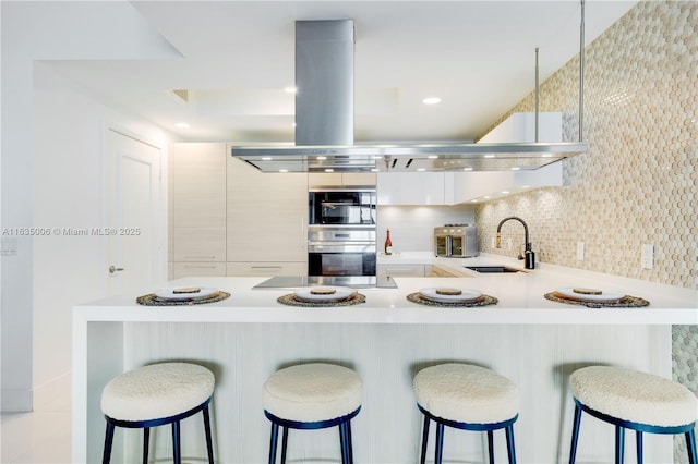 17111 Biscayne Blvd Unit 304, North Miami Beach, FL 33160 - kitchen with light countertops, modern cabinets, a peninsula, a breakfast bar area, and stainless steel double oven