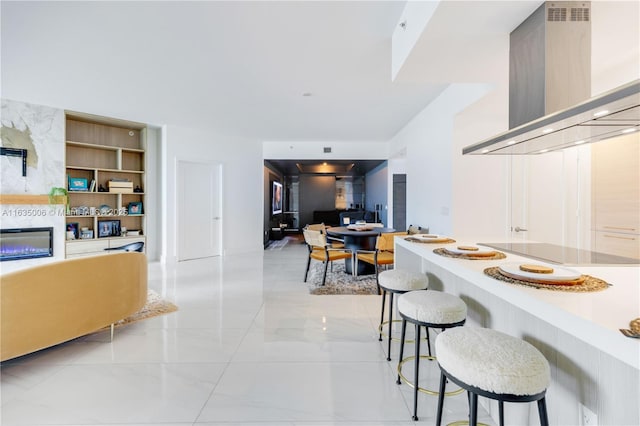 17111 Biscayne Blvd Unit 304, North Miami Beach, FL 33160 - kitchen featuring wall chimney exhaust hood, electric cooktop, a breakfast bar area, open floor plan, and a high end fireplace