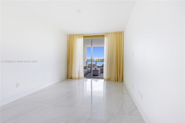 unfurnished room featuring a water view and a wall of windows