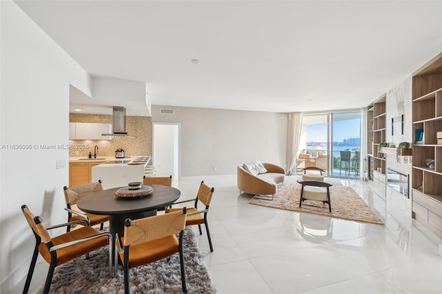 tiled dining room featuring expansive windows and sink