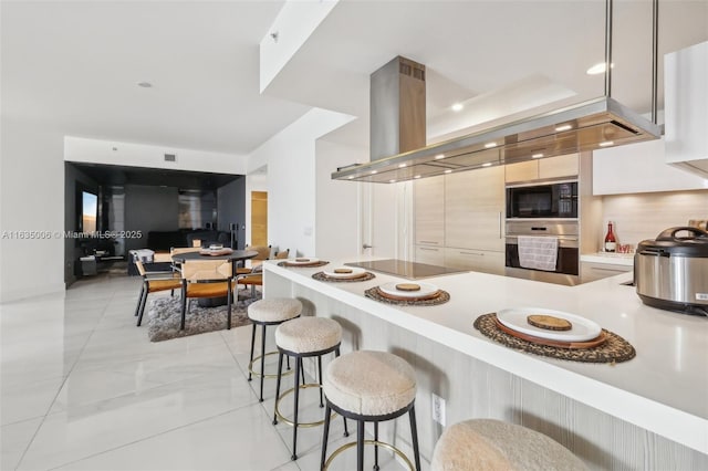 17111 Biscayne Blvd Unit 304, North Miami Beach, FL 33160 - kitchen featuring black appliances, light countertops, a kitchen bar, modern cabinets, and a peninsula