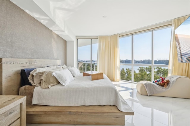 bedroom featuring a water view and expansive windows