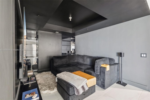 living room with a raised ceiling and light tile patterned floors