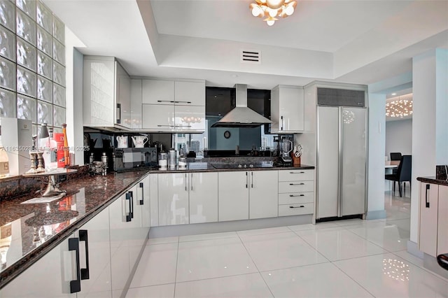 kitchen featuring light tile patterned floors, dark stone counters, visible vents, black appliances, and wall chimney exhaust hood