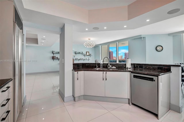 kitchen featuring sink, dark stone countertops, white cabinets, light tile patterned flooring, and stainless steel dishwasher