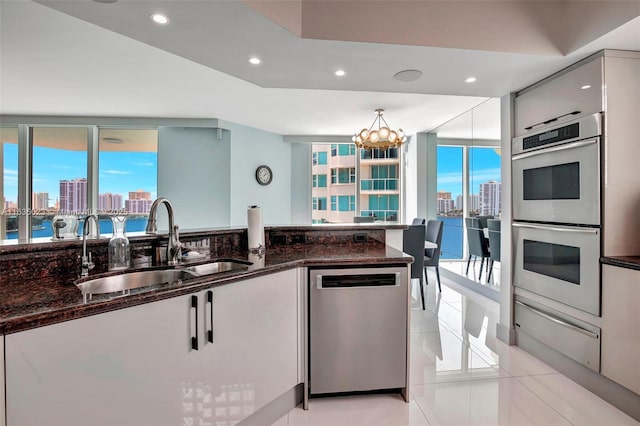 kitchen with a sink, appliances with stainless steel finishes, a view of city, and dark stone countertops