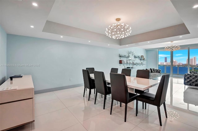dining space with a raised ceiling, a chandelier, baseboards, a view of city, and recessed lighting