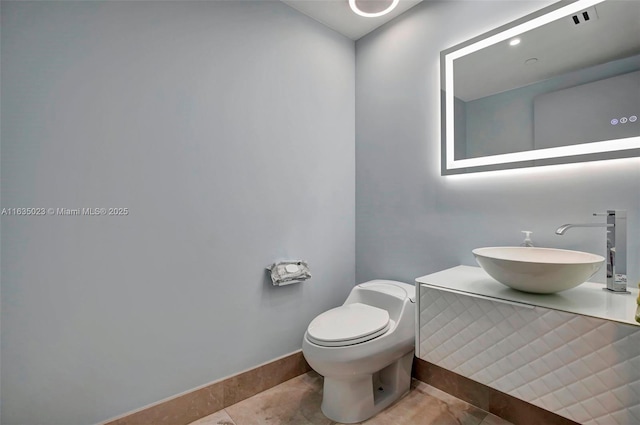 bathroom with baseboards, a sink, and toilet