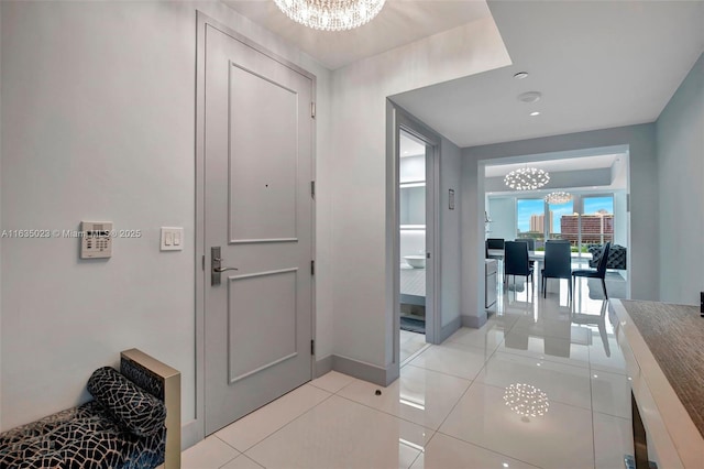 corridor with light tile patterned floors and an inviting chandelier