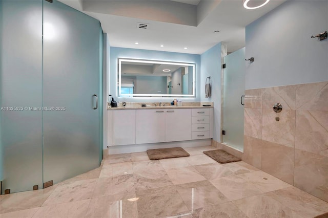 full bath featuring a sink, double vanity, a shower stall, and visible vents