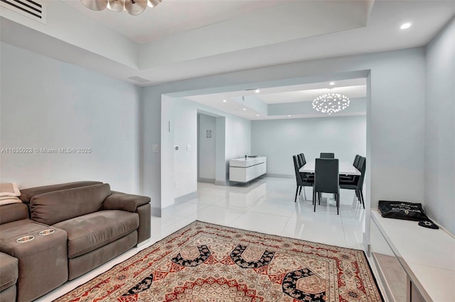 living room with a tray ceiling and light tile patterned floors