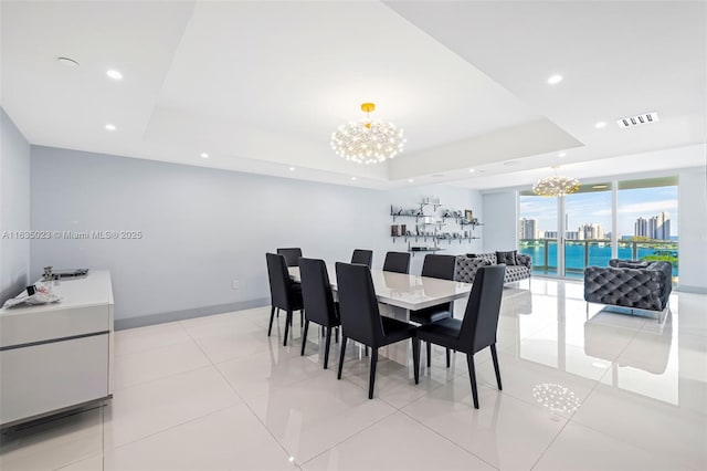 tiled dining area with a raised ceiling and an inviting chandelier