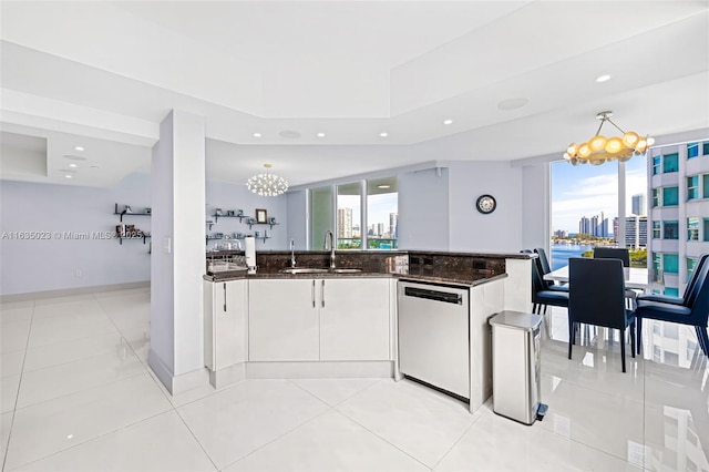 kitchen featuring a sink, dishwasher, an inviting chandelier, a view of city, and dark stone counters