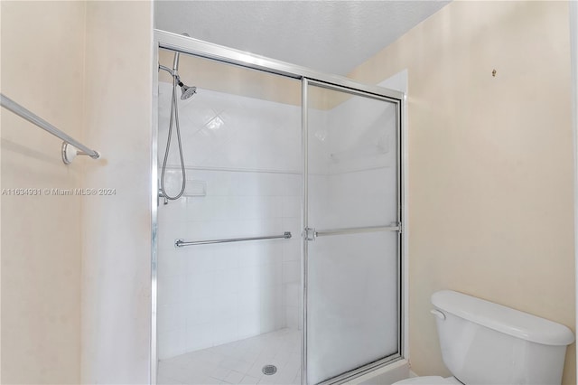 bathroom with a textured ceiling, toilet, and an enclosed shower