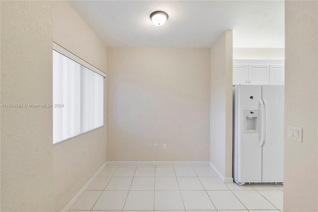 interior space featuring white cabinets, light tile patterned flooring, and white refrigerator with ice dispenser