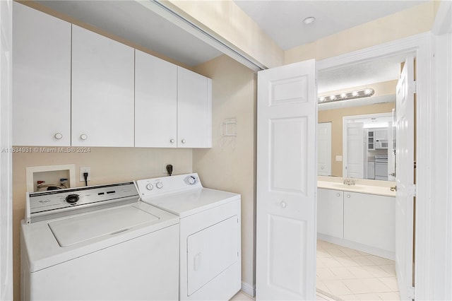 clothes washing area with washer and clothes dryer, sink, cabinets, and light tile patterned floors