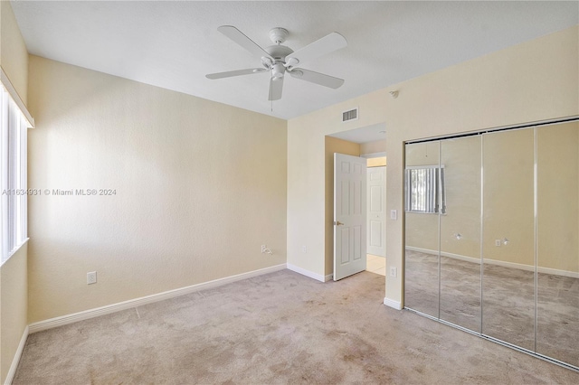 unfurnished bedroom featuring light colored carpet, a closet, and ceiling fan