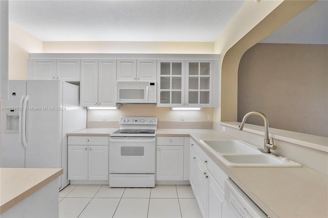 kitchen with sink, white cabinets, white appliances, and light tile patterned floors