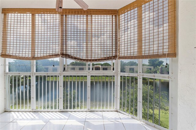 unfurnished sunroom with a water view, a wealth of natural light, and ceiling fan