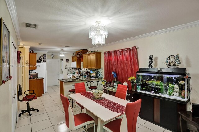 dining space with a textured ceiling, ornamental molding, light tile patterned floors, and an inviting chandelier