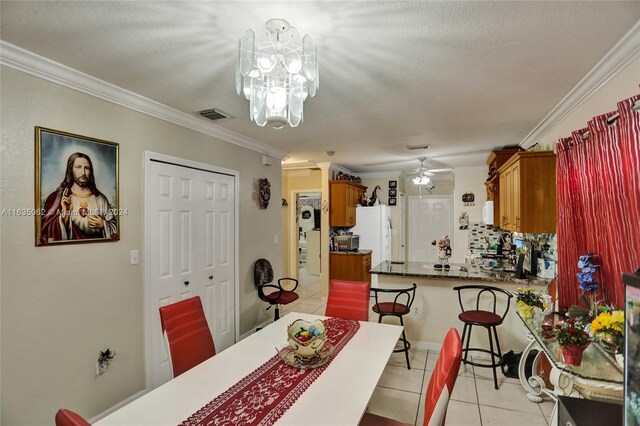 tiled dining area featuring crown molding and ceiling fan with notable chandelier