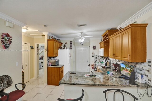 kitchen featuring light tile patterned flooring, backsplash, ornamental molding, ceiling fan, and kitchen peninsula