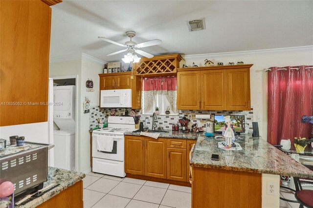 kitchen featuring white appliances, stacked washer and clothes dryer, ceiling fan, backsplash, and kitchen peninsula