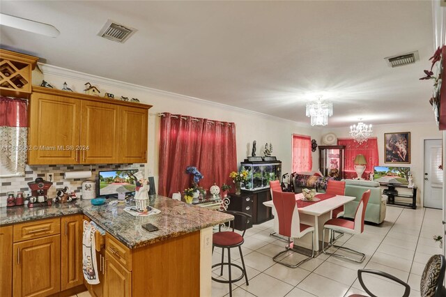 kitchen featuring light tile patterned floors, stone countertops, tasteful backsplash, ornamental molding, and an inviting chandelier