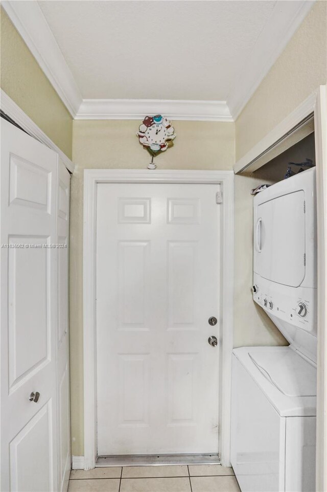 laundry area with light tile patterned floors, stacked washer and dryer, and ornamental molding