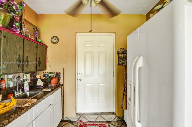 kitchen featuring ceiling fan, white cabinetry, light tile patterned floors, white fridge with ice dispenser, and sink