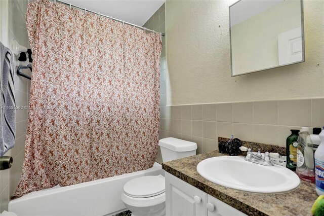 full bathroom featuring toilet, decorative backsplash, tile walls, shower / bath combo, and vanity