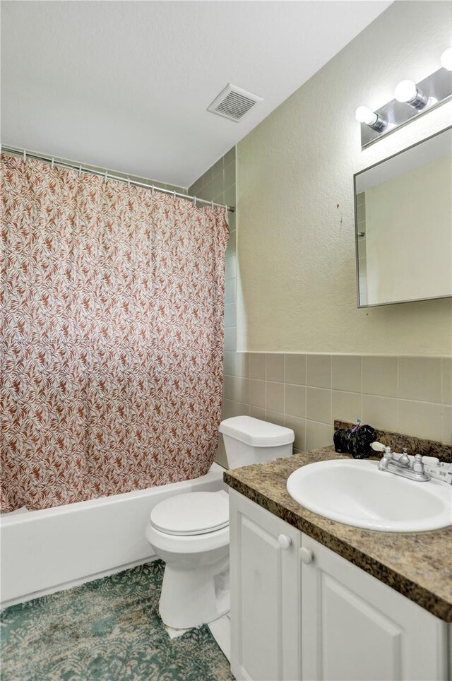 full bathroom with toilet, shower / bath combo, tile patterned floors, tile walls, and vanity