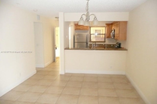 kitchen with a notable chandelier, light tile patterned floors, appliances with stainless steel finishes, pendant lighting, and sink