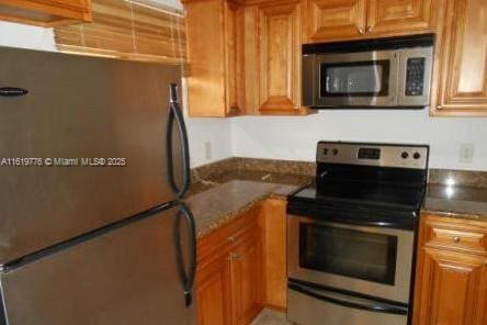 1482 Lake Crystal Dr Unit H, West Palm Beach, FL 33411 - kitchen featuring stainless steel appliances, brown cabinetry, and dark stone countertops